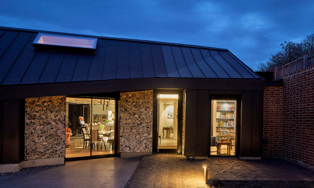 The outside of a building at dusk with a large roof window that is energy efficient.